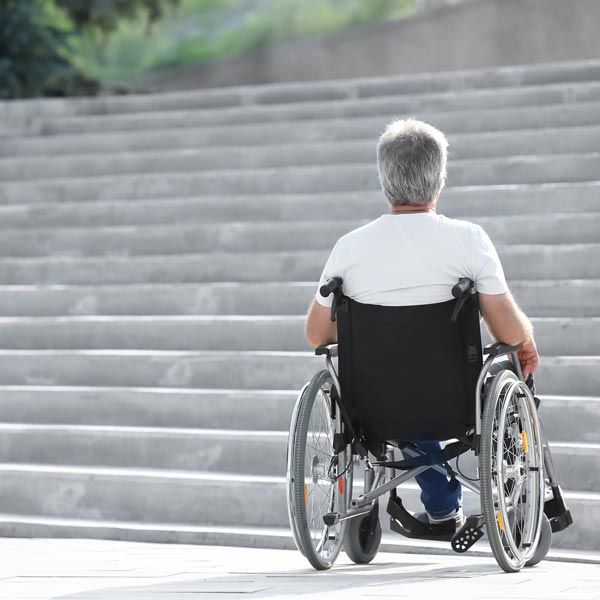 Man in wheelchair sitting at foot of stairs