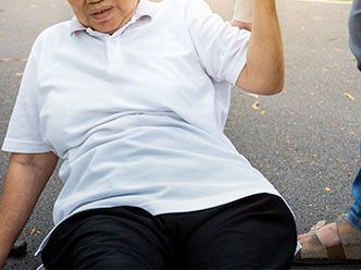 Passerby assisting elderly woman up from ground